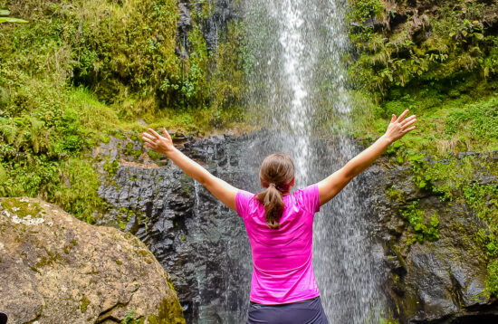 Guided hikers exploring the scenic Ragia Forest in Aberdare, Kenya, with waterfalls and lush bamboo forests in the background.