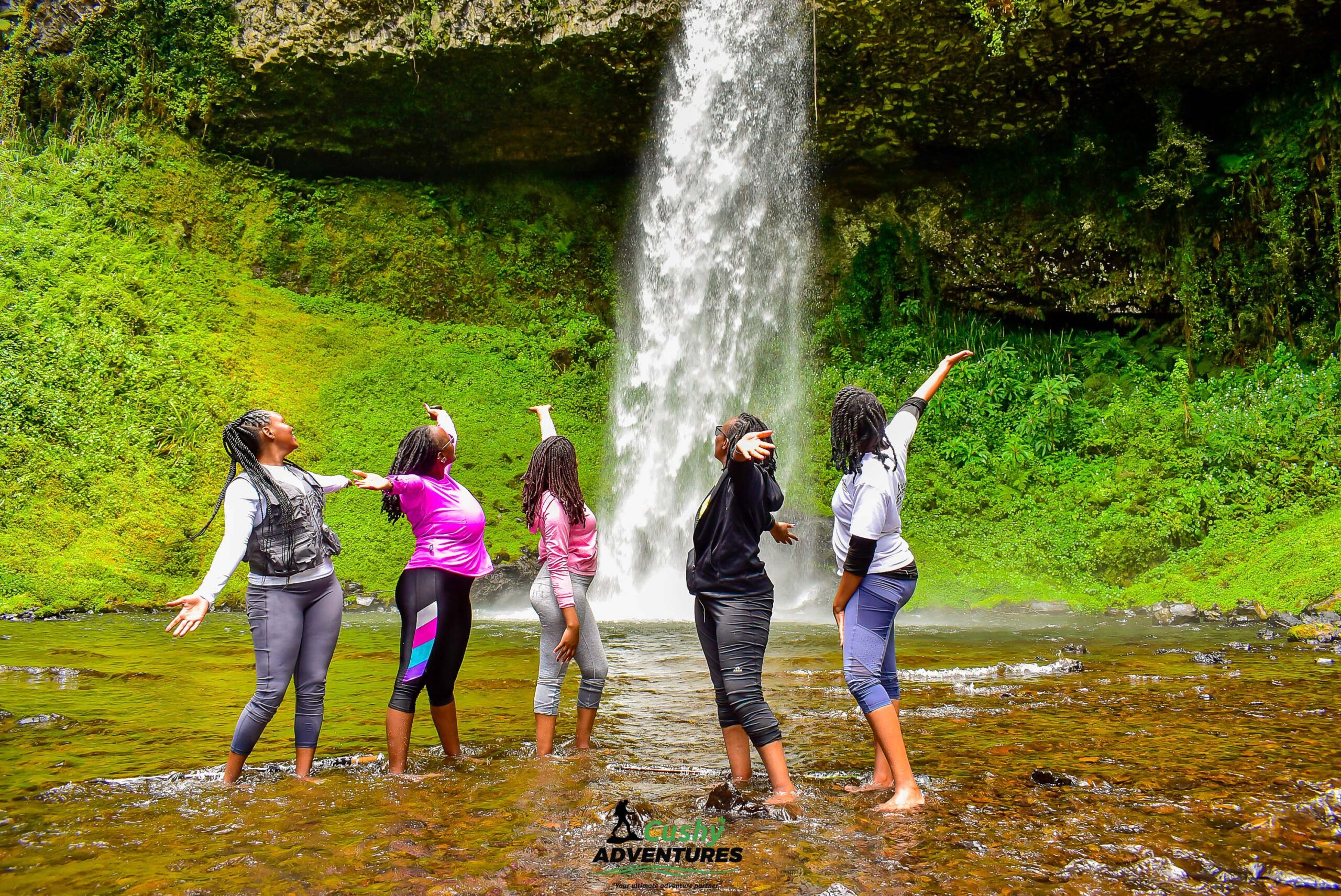 Five vibrant Cushy community ladies barefoot at waterfall