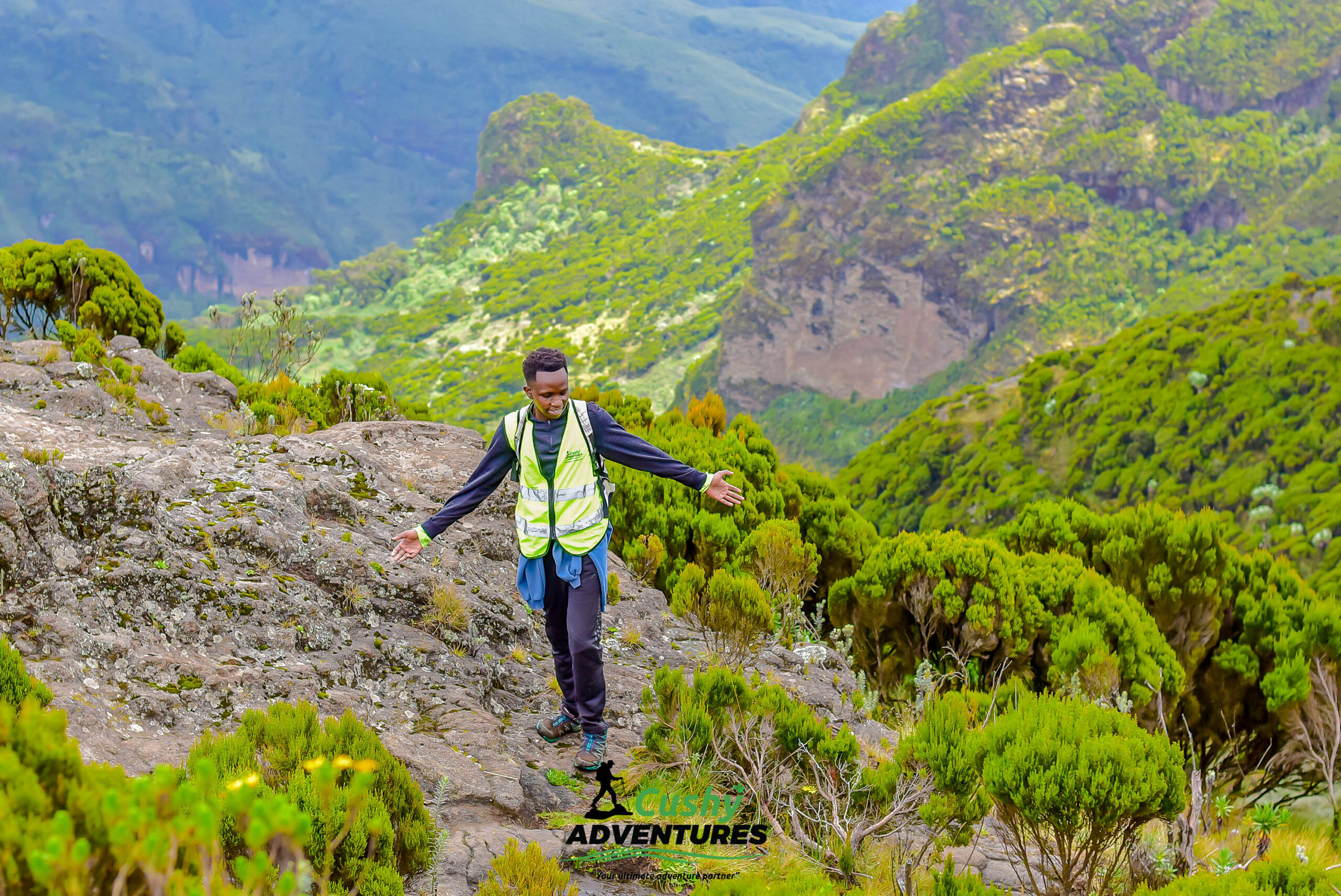 Cushy Adventures guide stretching arms while enjoying panoramic views near Elephant Hills summit.