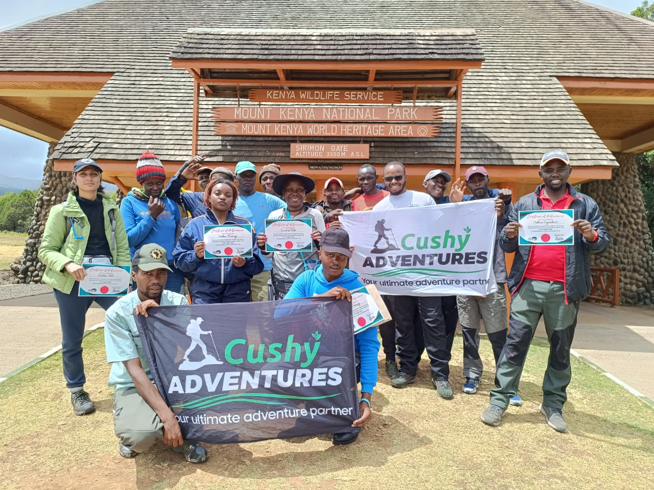 Group of Cushy Adventures hikers at Lenana Peak, Mt. Kenya, proudly holding summit certificates after successfully completing the Great Ascent Hiking Program.