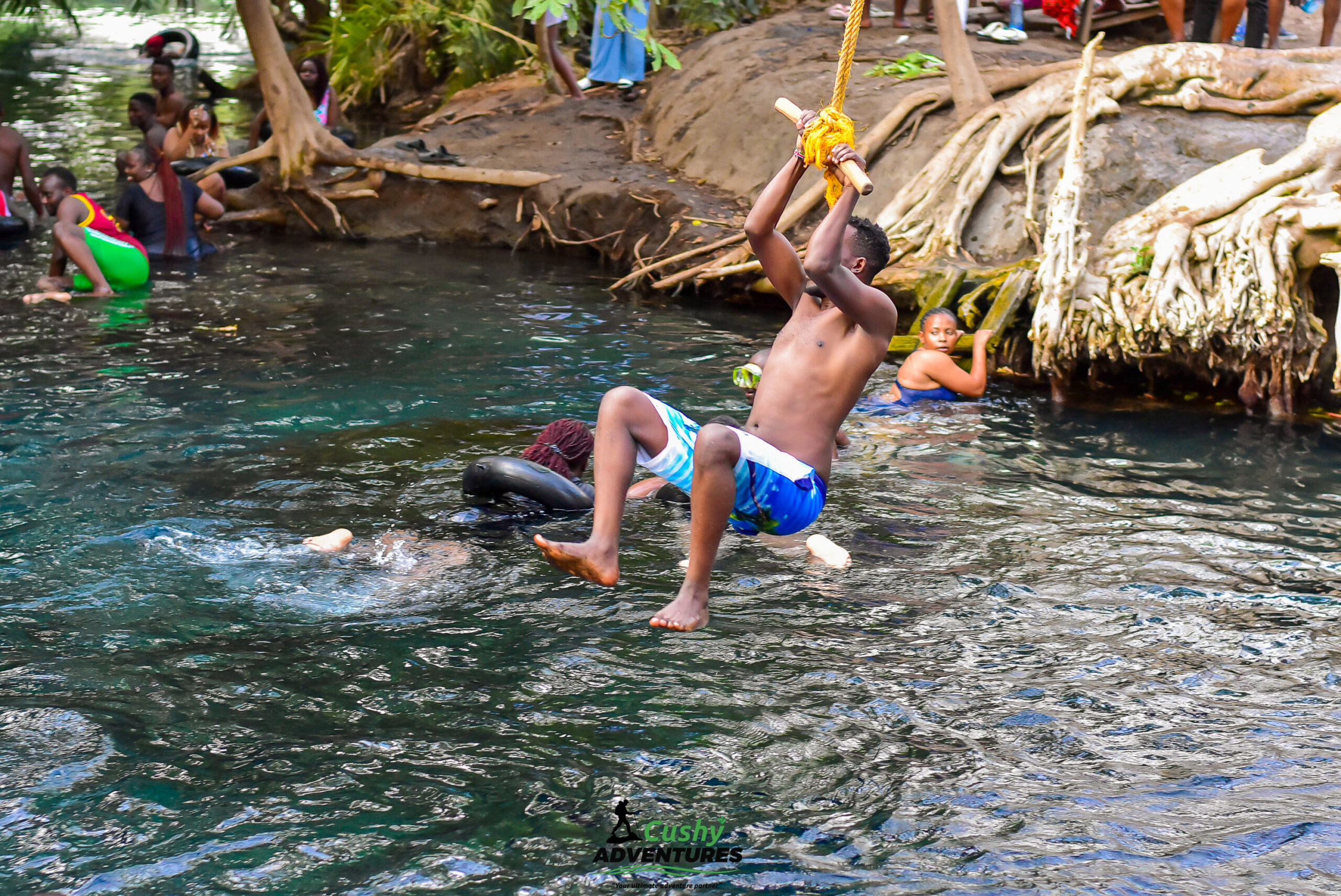Man diving into Kikuletwa Hot Springs using a rope swing with a tyre